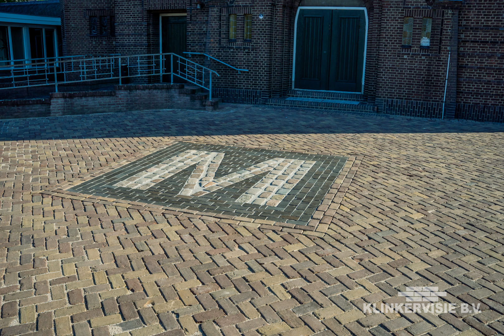 Historisch plein met M-monogram gelegd in oud gebakken klinkers
